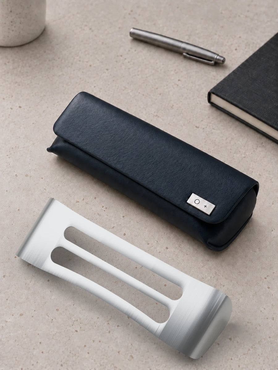 The closed navy case on a stone desk with a steel pen and a black notebook, and its bare titanium core lying in front of it.