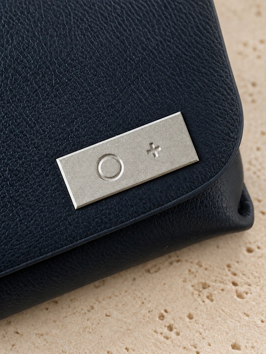 Close-up of the solid titanium O+ plate on the flap, engraved, with chamfered edges.