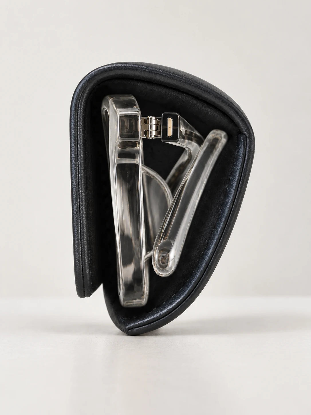 The open case seen end-on, standing upright, with a clear folded frame inside. An orange dotted line traces the space the frame takes up.